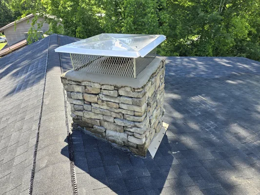 Stainless steel cap on stone chimney with flashing